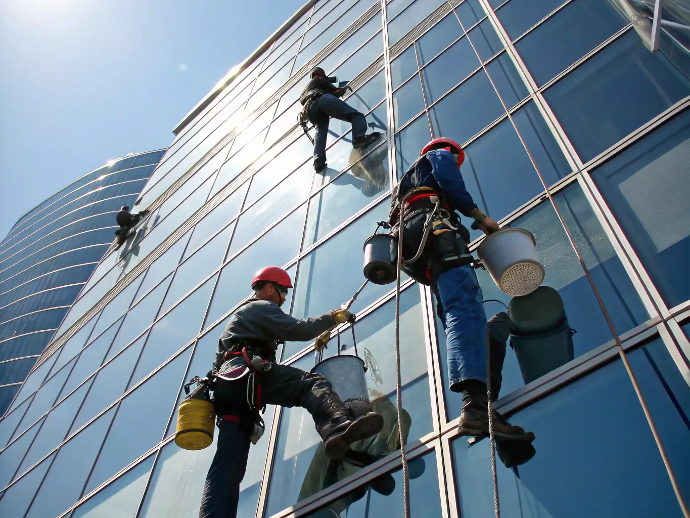 A team of IRATA-certified technicians performing a detailed inspection on a high-rise building using rope access techniques, showcasing their expertise and adherence to safety standards.